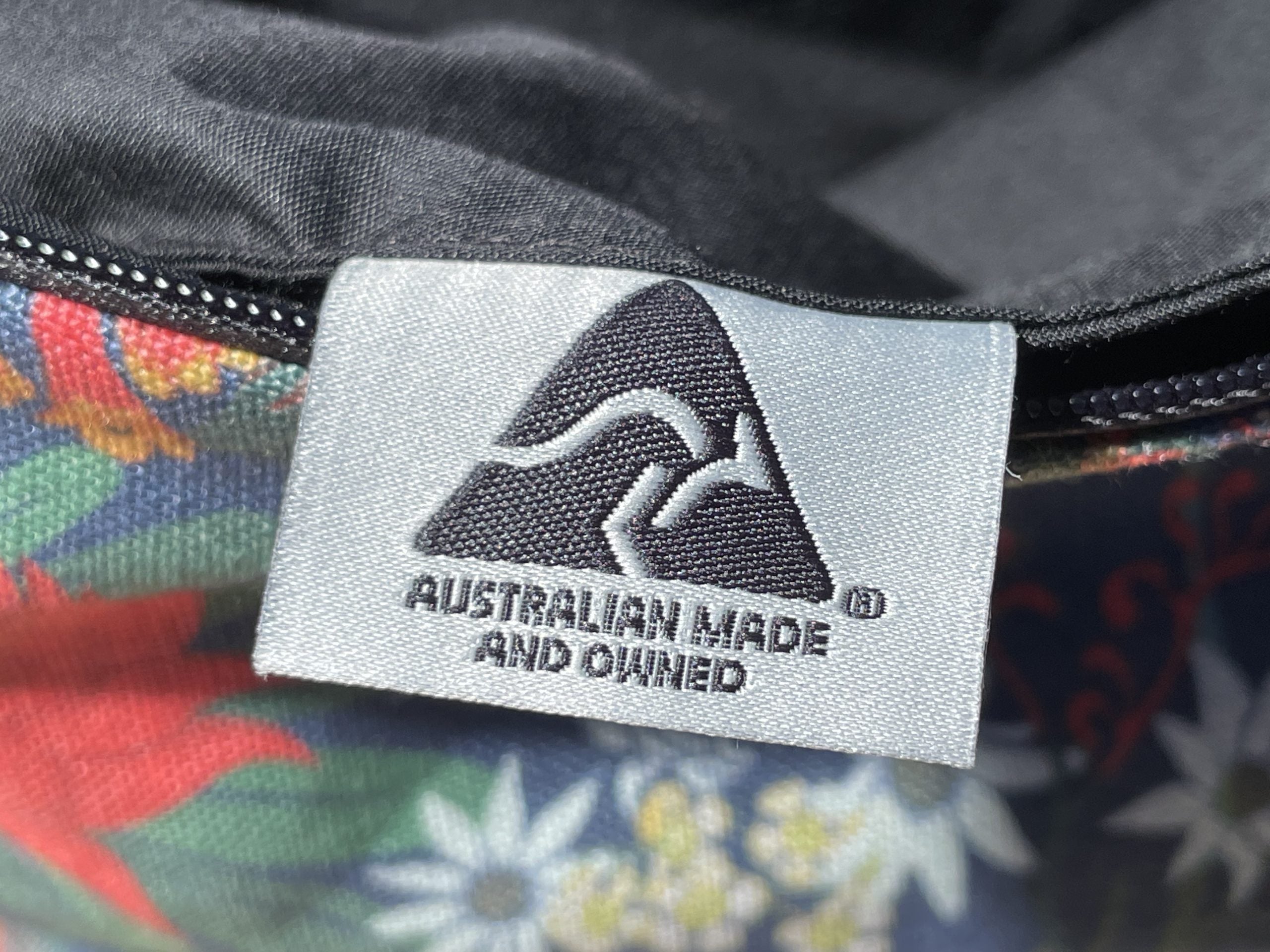 Label on a product indicating 'Australian Made and Owned' with a mountain design.