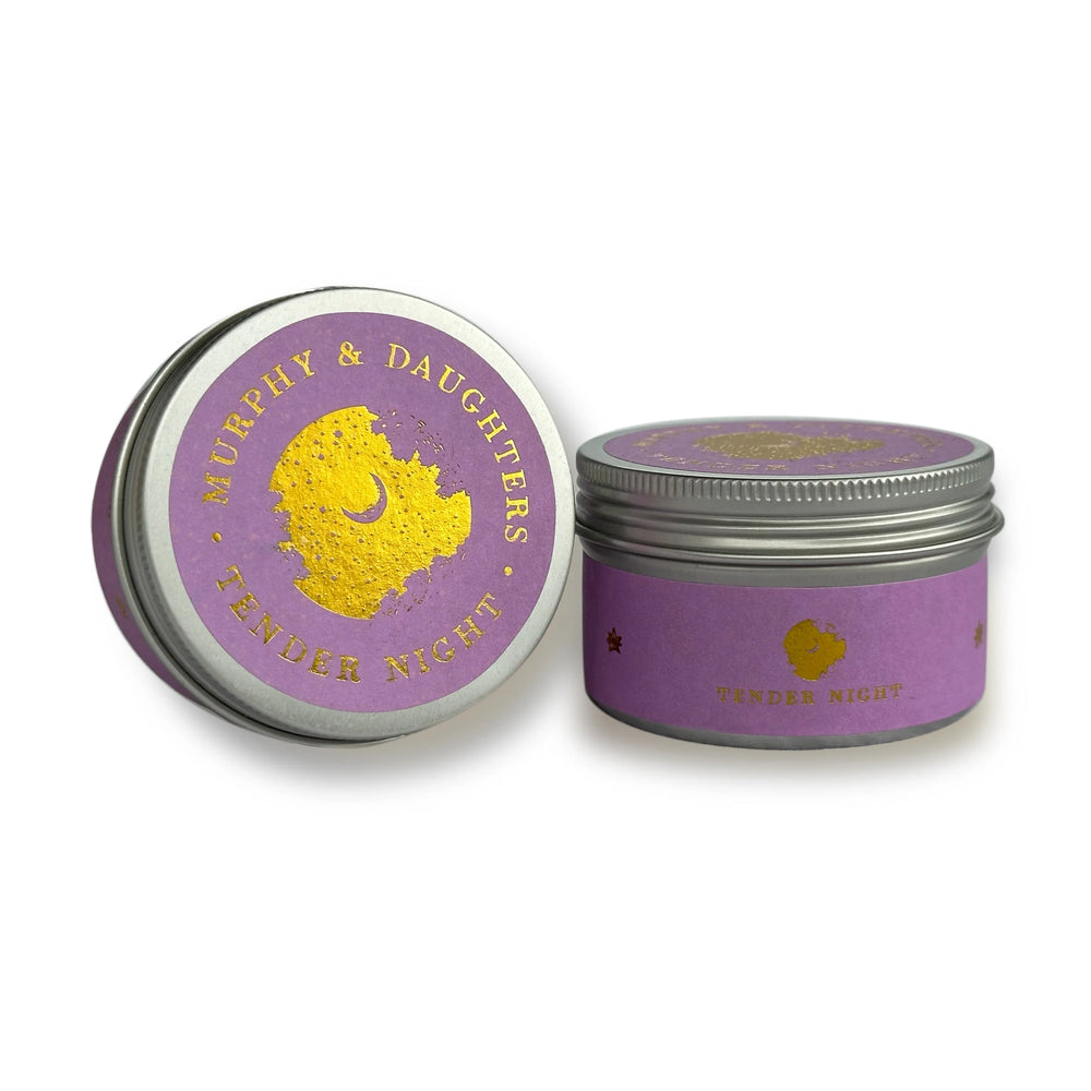 Two silver metal tins with lavender purple labels and gold foil detailing, one showing the lid design and the other the side label, on a white background.