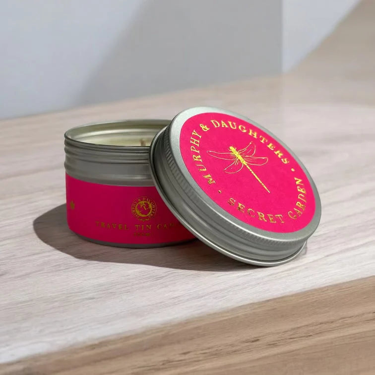Open tin with a pink label on top and a candle inside