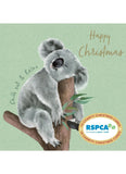 A Christmas greeting card featuring a sleeping koala on a tree branch against a light green background, with the text 'Happy Christmas' and 'Chill out & Relax'. An RPSCA logo badge appears in the lower right corner.