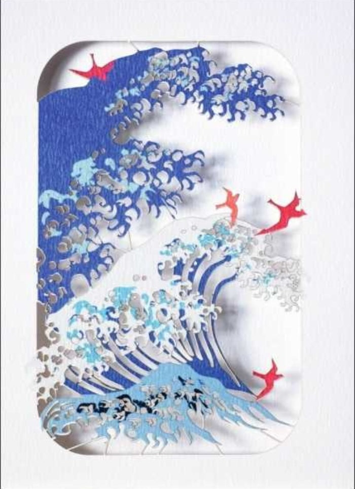 A cut out card with waves in blies and white with red birds
