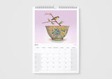 Calendar page for July with a decorative bowl and birds on a branch against a pink background