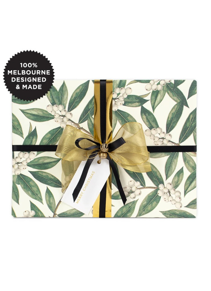Christmas gift wrapped in green and white wrap with a black and gold bow.