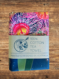100% cotton tea towel with colorful design on a wooden surface