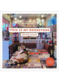 This is my Bookstore calendar cover with a cat reclining on a table of books surrounded by bookshelves
