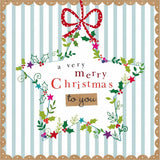 A square Christmas greeting card design with a white center panel reading 'a very merry Christmas to you' in red and black text, surrounded by a colorful holly and vine wreath and a red polka-dot bow at the top. The card has pale blue vertical stripes, a tan scalloped border, and decorative gold flourishes.