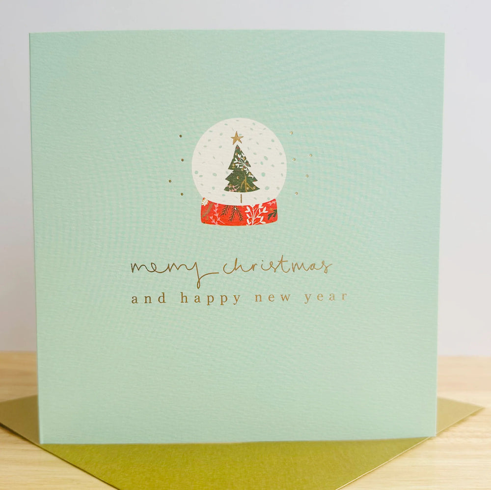A light green card with a snow globe and CHristmas tree and the words Merry Christmas and Happy New Year