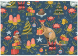A festive Christmas-themed pattern featuring a kookaburra, kangaroo, bird, Christmas trees, ornaments, presents, and protea flowers on a dark blue background.