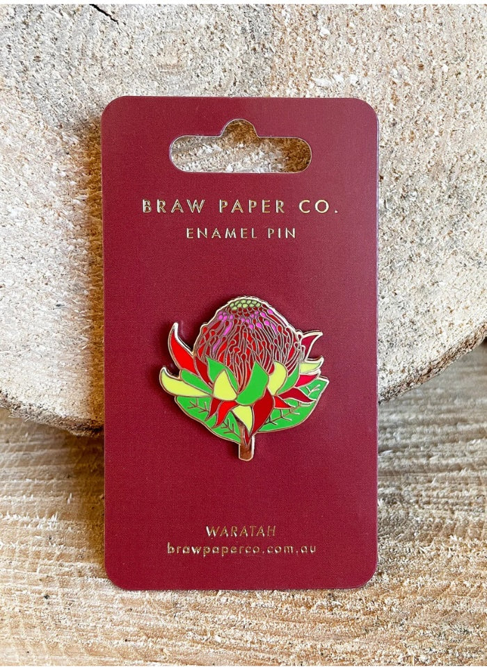 Enamel pin of a waratah flower on a Braw Paper Co. card with a textured background