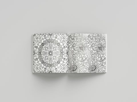 Coloring book open to pages with intricate black and white mandala designs on a gray background