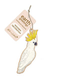 Wooden cockatoo decoration with 'earth greetings' tag on a white background