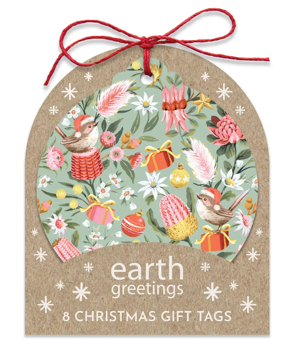 A kraft paper gift tag with a red hanging string and a large arched window showing a colorful Christmas illustration. The tag reads 'earth greetings 8 CHRISTMAS GIFT TAGS' and is shown on a white background.