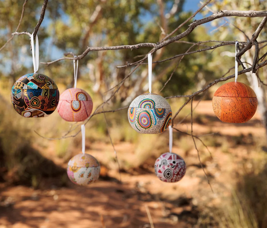 6 Christmas balls hanging on branches outside in the Australian bush