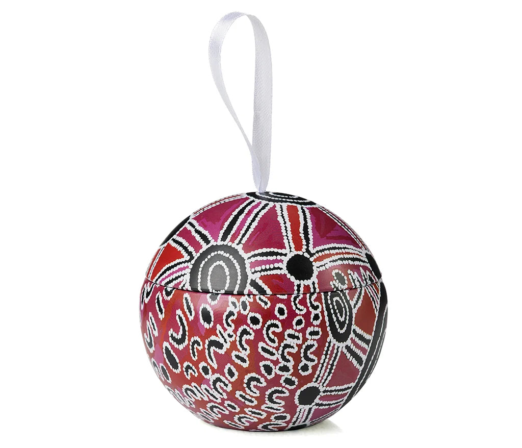 A Christmas bauble in an Aboriginal design on a piece of ribbon and a white background.