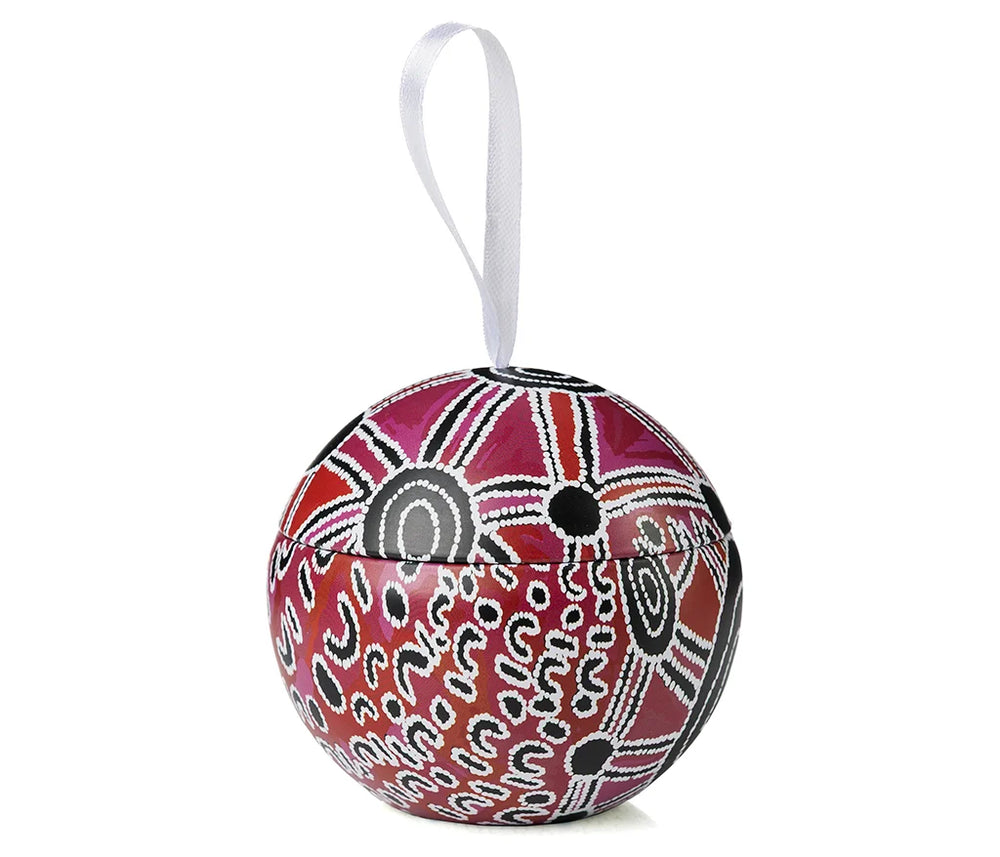 A Christmas bauble in an Aboriginal design on a piece of ribbon and a white background.