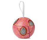 A Christmas bauble with Aboriginal art hanging from a ribbon on a white background