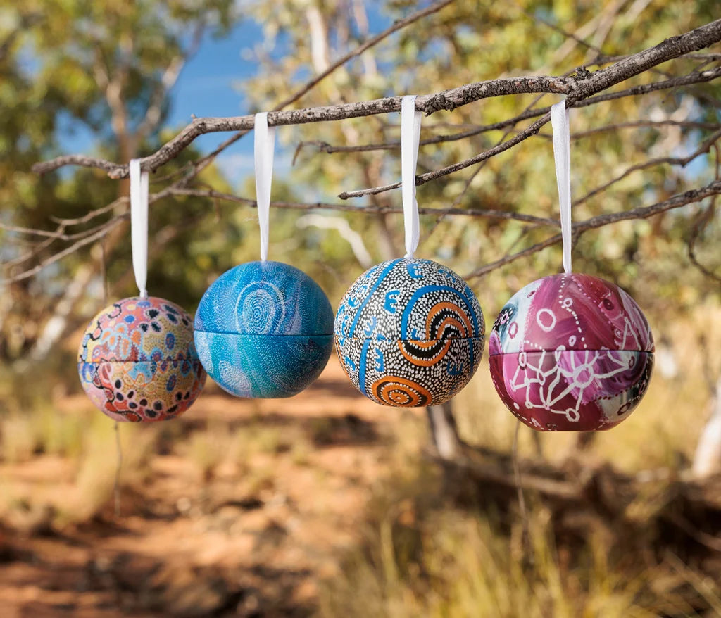 Colorful patterned balls hanging from a branch outdoors