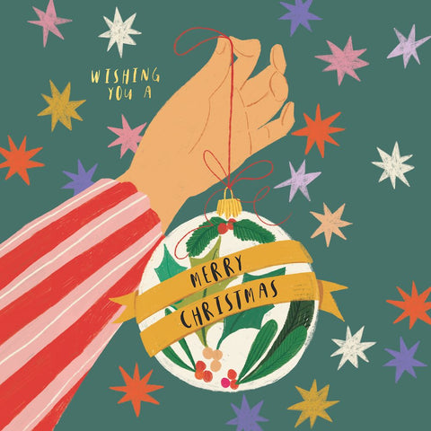 Illustration of a hand holding a Christmas ornament with 'Merry Christmas' text against a colorful star-patterned background.