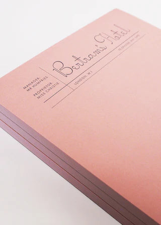 Pink notebook with 'Bertoni's Hotel' branding on a white background