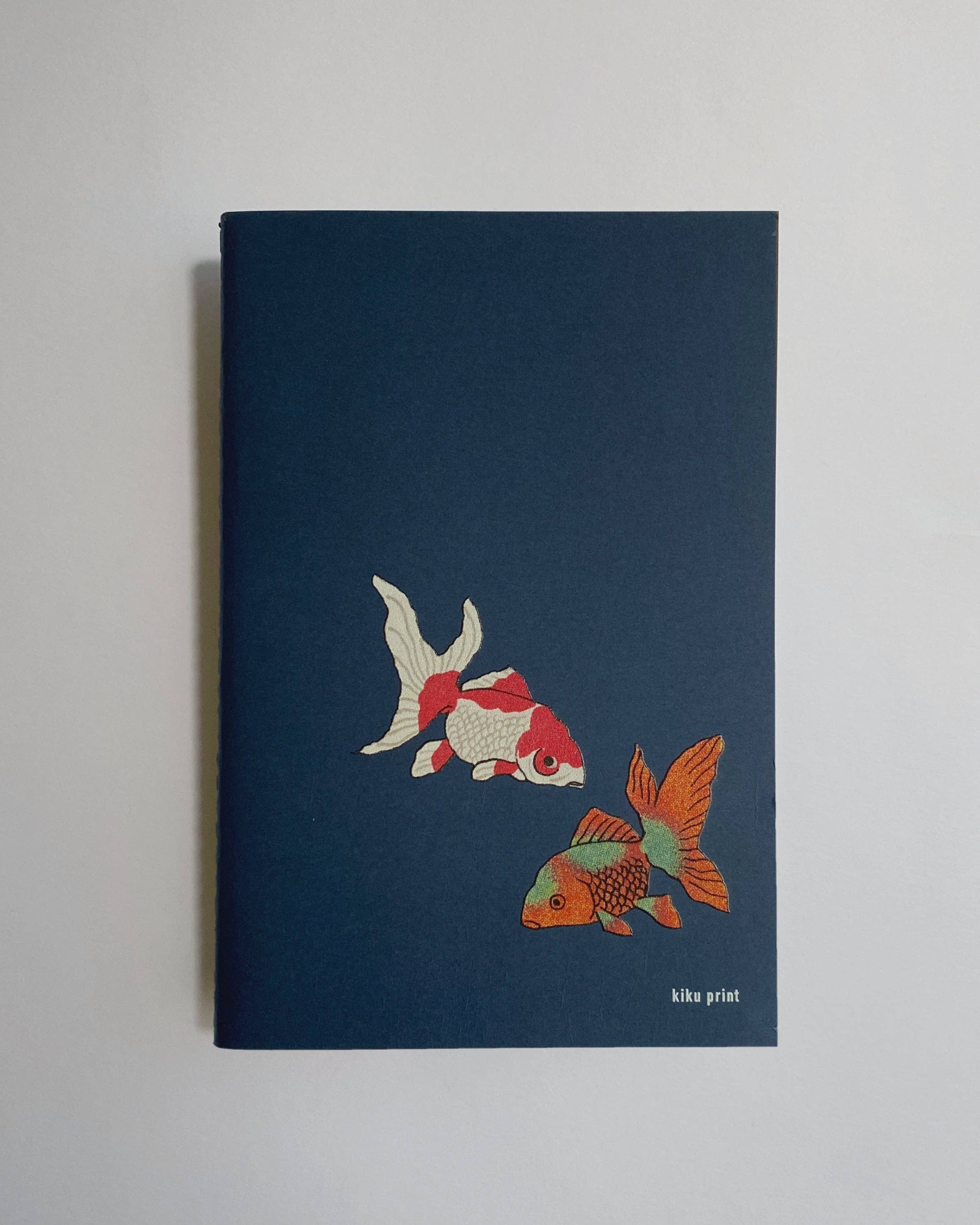 Notebook with goldfish illustration on a plain background