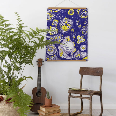 Decorative poster with floral design and text on a wall next to a guitar, chair, and plants.