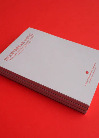 Stack of books titled 'Heartbreak & Rose' on a red background